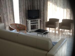 ein Wohnzimmer mit einem Sofa, Stühlen und einem TV in der Unterkunft Morgenzon Apartment in Nieuwpoort