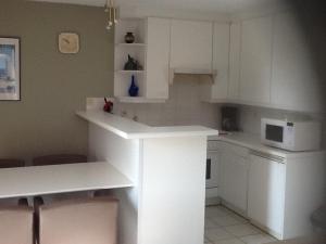 a white kitchen with white cabinets and a microwave at Morgenzon Apartment in Nieuwpoort