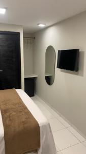 a bedroom with a bed and a flat screen tv at Aloha Noronha Suites in Fernando de Noronha