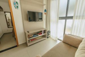 a living room with a television on a wall at Apê aconchegante a 50m do mar - Maracaípe in Porto De Galinhas +40 photos