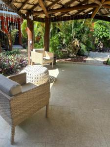a patio with wicker chairs and tables under a pergola at Vilarejo do farol in Praia do Forte
