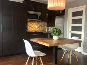 a kitchen with a wooden table and white chairs at L'intime loft Studio à Orford in Magog-Orford