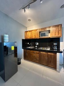 une cuisine avec des armoires en bois et un réfrigérateur noir dans l'établissement Loft privado cerca del Jardín Principal de Sayula, à Sayula