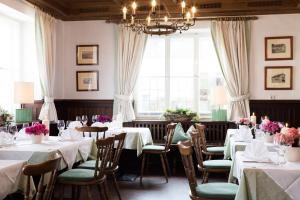 a dining room with white tables and chairs and windows at Hotel Sollner Hof in Munich