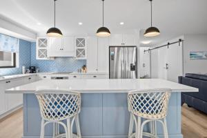 une cuisine avec une grande île blanche et bleue avec deux chaises dans l'établissement Waves Retreat - Coastal Style Home near Warana Beach, à Parrearra 17 autres photos