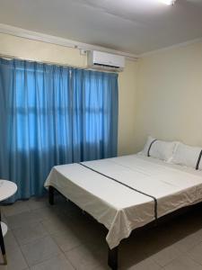 um quarto com uma cama grande e cortinas azuis em Nadi Airport rooms em Nadi