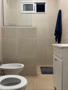 Un baño con inodoro blanco y ventana. en El Buen Vivir, en Mar del Plata