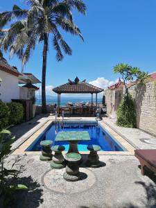 a swimming pool with a table and a gazebo at Bali Budget Beach Bungalow in Candidasa