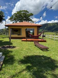 a small house with a hammock in a yard at Mirante do Sol 1 - café da manhã, hidro e lareira in Córrego do Bom Jesus