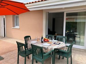 una mesa con sillas verdes y una sombrilla roja en Terraced holiday home in Moliets, en Moliets-et-Maa 25 fotos más