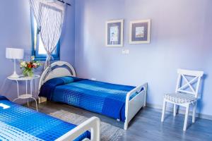 a blue bedroom with two beds and a chair at Eva's House in Stroumbi