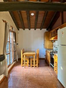 a kitchen with a table and chairs and a refrigerator at Cabañas Las Rosas in Maipú