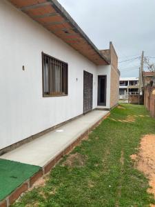 a white house with a window and a yard at Casa na praia em Torres my house in Torres in Torres