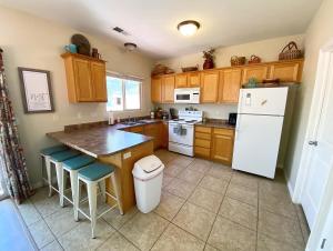 eine Küche mit Holzschränken und einem weißen Kühlschrank in der Unterkunft Pool & Hot Tub Close to hiking trails in Kanab in Kanab