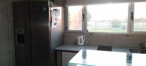 a kitchen with a refrigerator and two windows at monoambiente grande, pileta arroyo seco in Arroyo Seco +3 photos