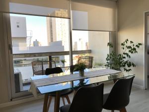 a dining room with a table and chairs and a large window at Departamento JACARANDA con cochera in Bahía Blanca