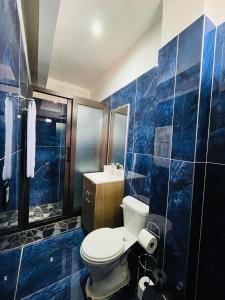 a blue tiled bathroom with a toilet and a shower at Casa El Borde Del Lago in Panajachel
