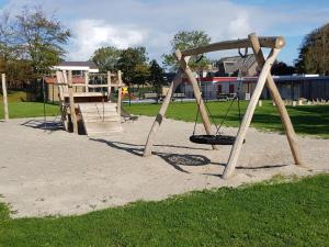 a playground with a swing set in a park at Chalet in Friesland near Wadden Sea in Tzummarum +29 photos