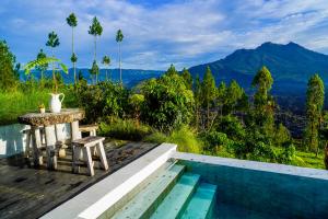 a table and stool next to a pool with a view at W Green Kintamani in Kintamani