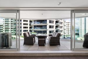 a patio with chairs and a table on a balcony at A Strand of Paradise, Oceanside Views & Pool in Mount Maunganui