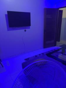 a purple room with a fan and a tv at Tige logement in Dakar