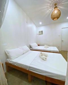 two beds in a room with white sheets and towels at Mandala Beach Cebu by Hiverooms in Medellin +13 photos