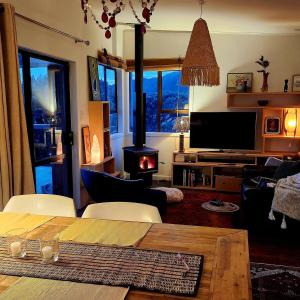 a living room with a table and a wood stove at Beachfront Sunset Bach in Piha