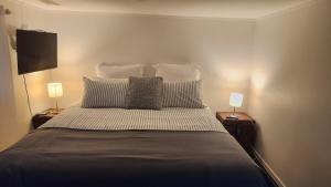a bedroom with a large bed with two lamps at Beachfront Sunset Bach in Piha