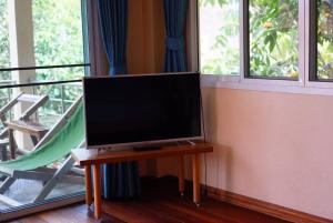 a flat screen tv sitting on a table next to a window at Baan Ob-oun Homestay in Ban Khlong Chi Lat