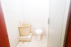 a white bathroom with a toilet and a sink at Astri Homestay Carkranegara Mataram Mitra RedDoorz in Tjakranegara