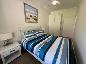 a bedroom with a bed with a blue and white striped blanket at The Mac Shack (SA) Pty Ltd in Port Vincent
