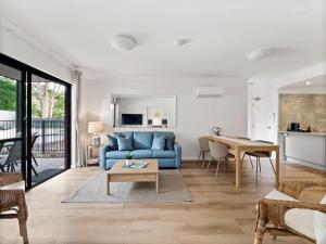 Una sala de estar con un sofá azul y una mesa. en Moo's Hoose, en Margaret River Town