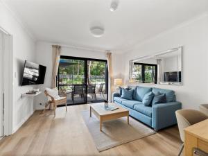 Una sala de estar con un sofá azul y una mesa. en Moo's Hoose, en Margaret River Town