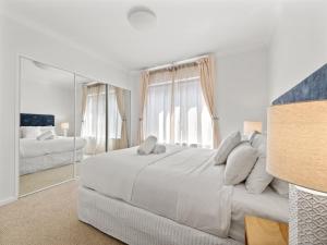 Un dormitorio blanco con una cama grande y un espejo. en Moo's Hoose, en Margaret River Town 26 fotos más