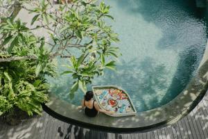 a woman sitting in a pool at a resort at Ecozy Dijiwa Canggu in Canggu
