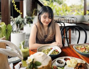 a woman sitting at a table with a bowl of food at Ecozy Dijiwa Canggu in Canggu