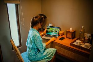 a woman sitting at a desk with a laptop computer at Ecozy Dijiwa Canggu in Canggu
