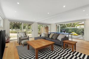 a living room with a couch and a table at Coastal White House in Point Lonsdale