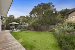 a backyard with a lawn and a wooden deck at Coastal White House in Point Lonsdale