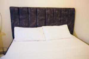 a bed with white sheets and a brown headboard at Cosy home in Maralal