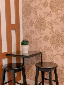 una mesa y dos taburetes con una planta en la pared en Toffee Staycation, en Tagaytay