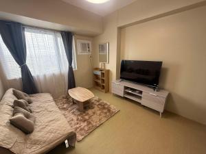 a living room with a couch and a flat screen tv at Amoore Avida Tower 2 in Cagayan de Oro