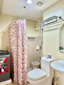 a bathroom with a toilet and a shower curtain at Amoore Avida Tower 2 in Cagayan de Oro