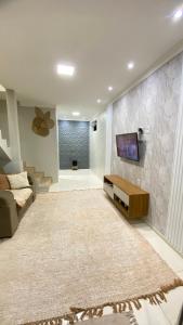 a living room with a couch and a tv on a wall at Casa Beira Mar in Santa Cruz Cabrália