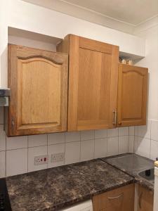 a kitchen with wooden cabinets and granite counter tops at Cosy Spacious Studio Flat,N18 in London