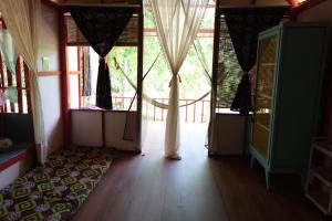 a room with a large window with curtains and a wooden floor at Presente in Ko Phayam