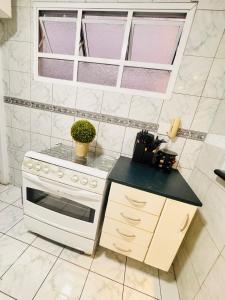 a kitchen with a white stove and a sink at Apartamento em Guarujá - Praia da Enseada in Guarujá
