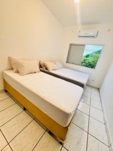 two beds in a room with a window at Apartamento em Guarujá - Praia da Enseada in Guarujá