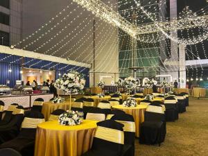 a banquet hall with yellow tables and chairs and lights at Hotel Amer Green's in Bhopal
