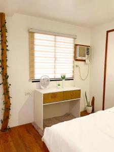 a bedroom with a bed and a window with a desk at KnowWell Siargao Nâked in General Luna
